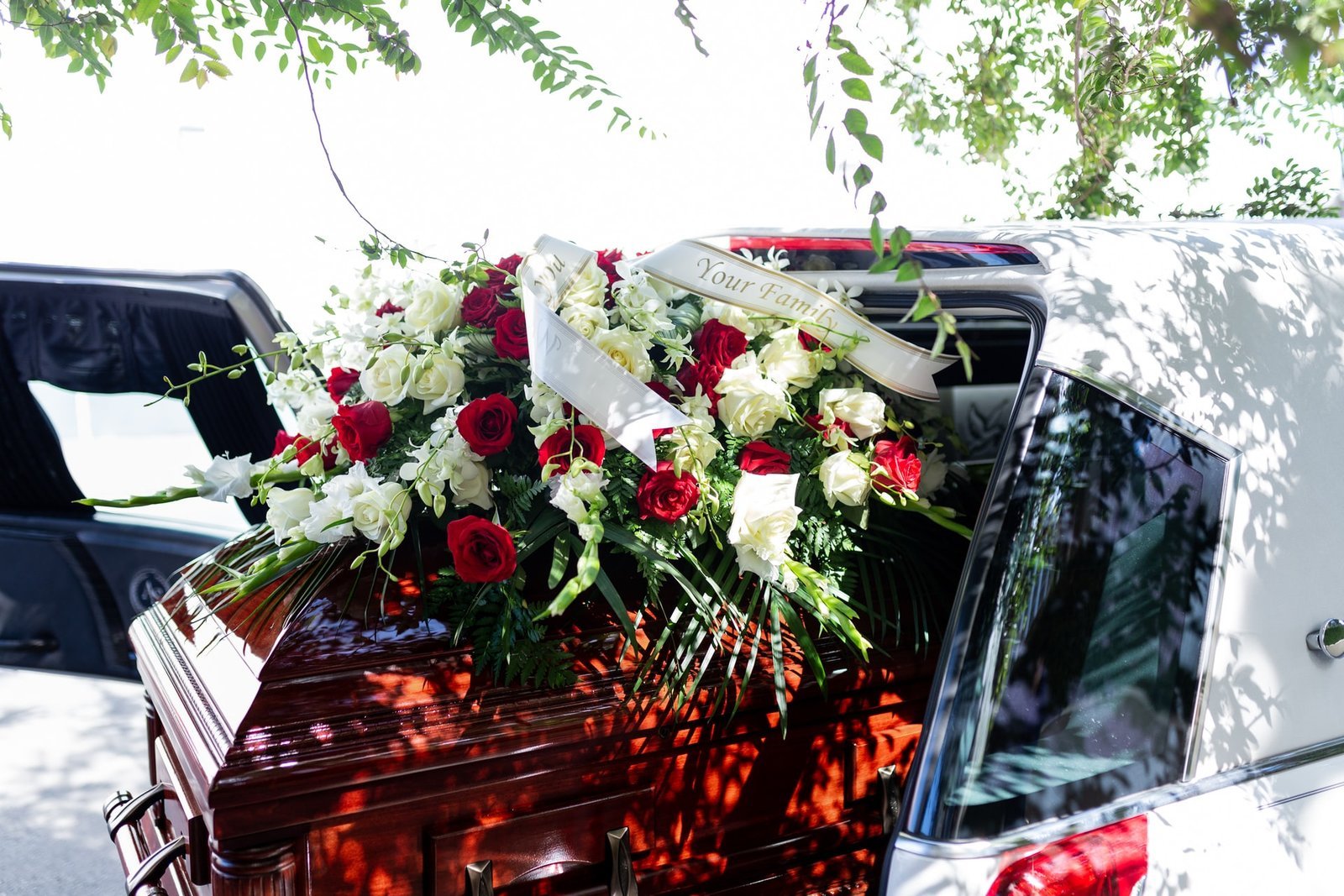 Arreglo floral rojo y blanco sobre carroza funeraria